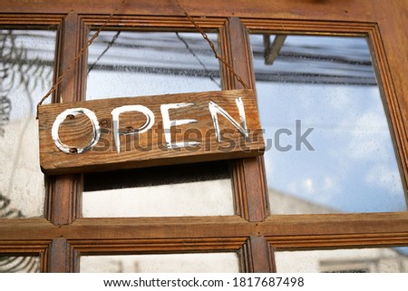 A wooden sign in front of the coffee shop hung at the entrance of the store with a message open during the virus outbreak.