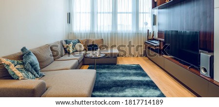 Modern interior of luxury apartment. TV on wall unit. Cozy couch. Window with tulle. Coffee table.