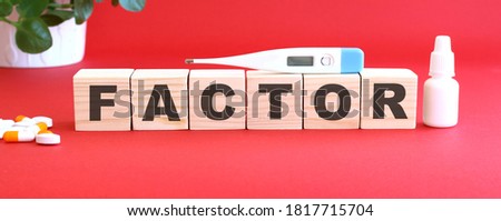 The word FACTOR is made of wooden cubes on a red background with medical drugs. Medical concept.
