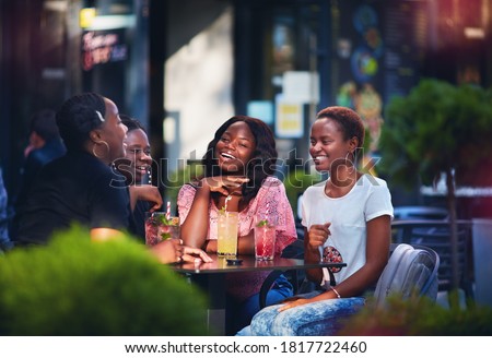 Happy African American Women, friends sitting together at the outdoor restaurant at summer day Royalty-Free Stock Photo #1817722460