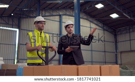 Warehouse worker and manager checking product in a large warehouse