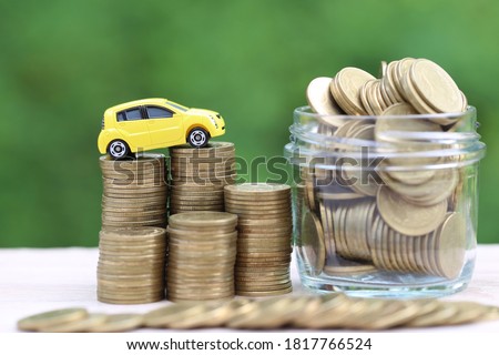 Miniature yellow car model on growing stack of coins money on nature green background, Saving money for car, Finance and car loan, Investment and business concept
