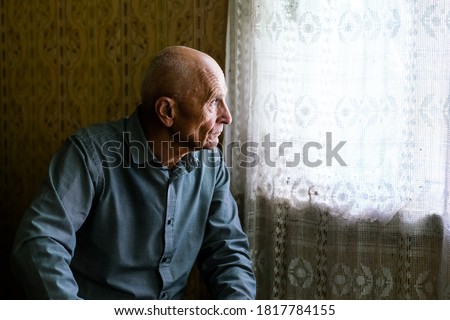 older sad bald man siting on sofa in village house and looking to window senior persons concept Royalty-Free Stock Photo #1817784155