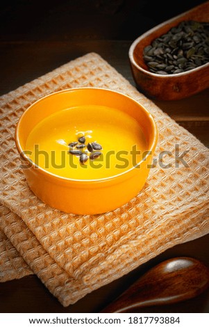 Bowl of tasty pumpkin soup and space for text on brown table, top view