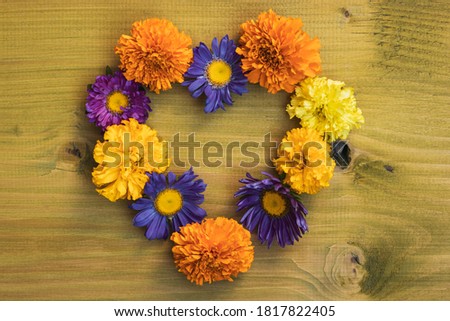 Image of heart shape made with  beautiful flowers on wooden background. 