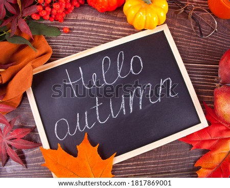 Chalkboard with Hello Autumn text. Composition with pumpkin, autumn leaves and red pears. Cozy autumn mood concept.
