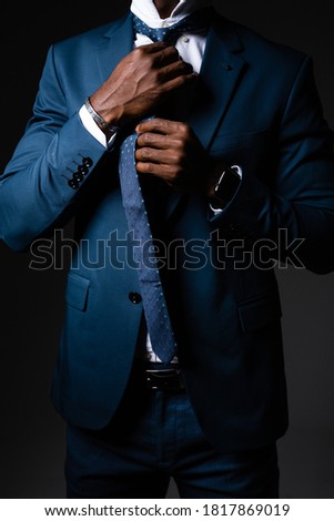 A man in a business suit straightens his tie around his neck.