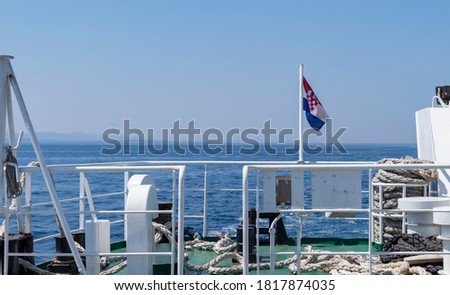 Croatian flag swaying on the ferry boat leaving Sucuraj port on the Hvar island, transfering cars and tourists to mainland