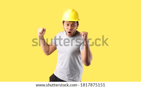 Asian man Industry worker or engineer working an architect builder Happy excited raising his fists on yellow background in studio With copy space.
