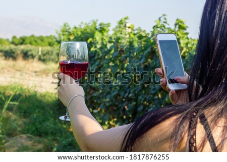 The woman shoots a glass of wine in the grape garden
