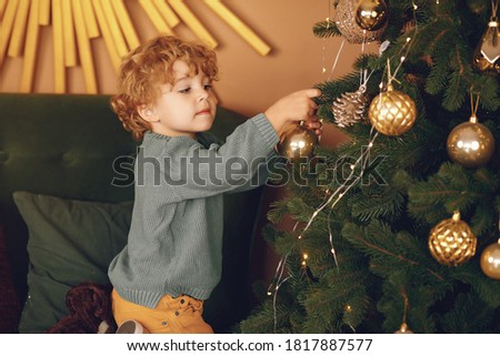 Cute little boy in a studio. Child standing near christmas tree. Kid in a gray sweater.