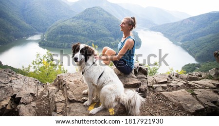 woman and dog on mountain top above lake