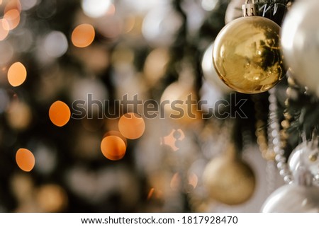 Blurred picture of christmas tree with gold lights and silhouette of spruce branch. Defocused new year background with space for text. Concept of new year advertisment