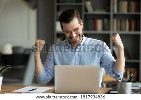 Overjoyed millennial male worker in glasses look at laptop screen triumph get pleasant promotion email. Excited young man feel euphoric reading good unexpected news online on computer. Luck concept. Royalty-Free Stock Photo #1817934836