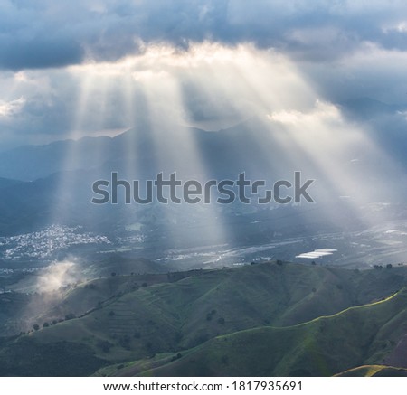 dramatic image of sunlit mountains of the caribbean with a approaching storm and clouds in dominican republic.