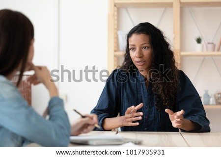 Confident African American woman candidate speaking at job interview, answering hr manager employer questions, diverse business partners colleagues discussing project strategy, sharing ideas Royalty-Free Stock Photo #1817935931