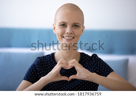 Headshot portrait of happy young hairless woman beat cancer look at camera show heart love gesture sign with hands. Smiling bald female oncology patient feel optimistic support sick people, volunteer.