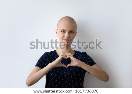 Headshot portrait of young hairless sick woman suffer from cancer show heart love hand sign or gesture. Profile picture of bald female patient struggle with oncology, show support. Remission concept.