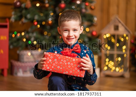 Christmas fabulous, little boy holding a big red box with a present from Santa.