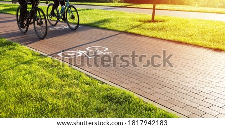Bike lane in the city public park. Two cyclists ride the bike path early in the morning. Healthcare and active lifestyle. Royalty-Free Stock Photo #1817942183