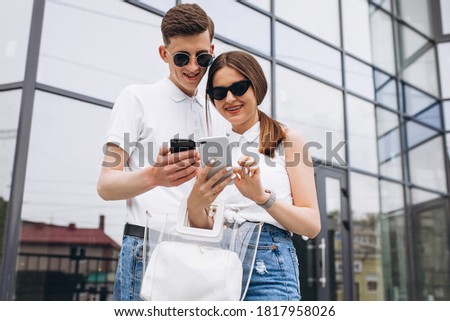 Happy couple together out in the city using phone
