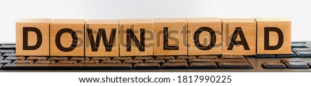 DOWNLOAD word on block concept. DOWNLOAD word made with building blocks. A row of wooden cubes with a word written in black font is located on a keyboard.