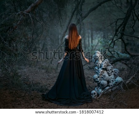 Mysterious silhouette of a ghost woman in a black vintage long dress. Gothic pagan lady near many skulls of dead people. The vampire walks in a deep dark mystical forest. Back rear view.