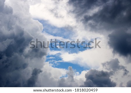 A hole in the stormy clouds revealing the blue sky in the background