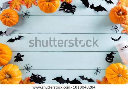 Top view of Halloween crafts, orange pumpkin, ghost, bat and spider on  pastel wooden background with copy space for text. halloween concept.
