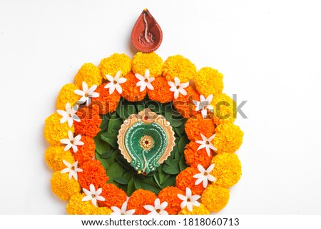 Flower Rangoli for Diwali Festival made using Marigold and leaf and Oil Lamp over white background,