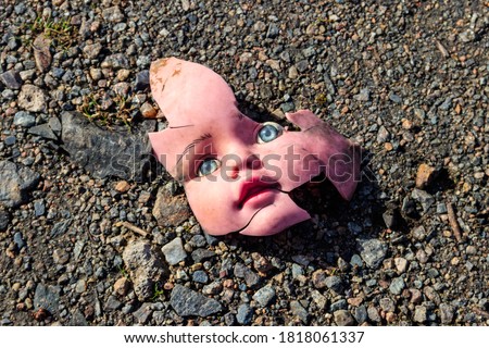 Old broken doll face on ground Royalty-Free Stock Photo #1818061337