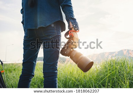 Young Asian woman photographer holding dslr camera at mountain peak.