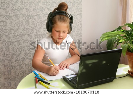Focused kid self isolation wearing headphones using laptop at home, writing notes,student girl learning language, watching online webinar, Home schooling, e-learning education concept Royalty-Free Stock Photo #1818070118