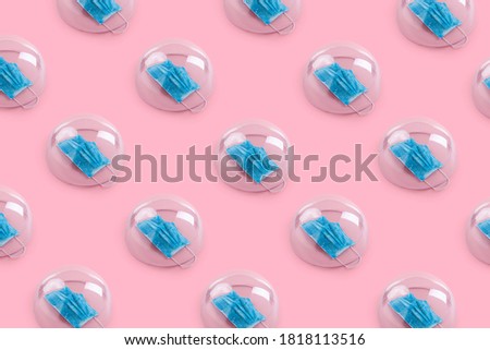 Pattern  made of face masks trapped in glass cloche on pink colored background. Creative isolation or quarantine idea. New Corona virus , COVID-19, or 2019-ncov infection idea. Flat lay. Royalty-Free Stock Photo #1818113516