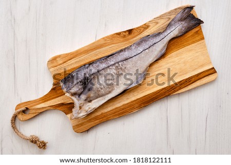 Top view of raw fresh haddock carcass on wooden cutting board