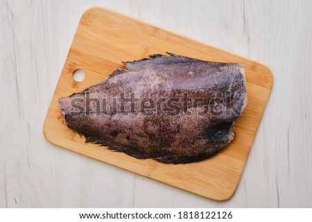 Top view of raw fresh halibut without head on wooden cutting board