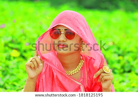 A closeup portrait Image of Indian beautiful young woman face with wearing pink colored Traditional Rajasthani rajputi dress and shiny stylish glasses. outdoors blur background of nature