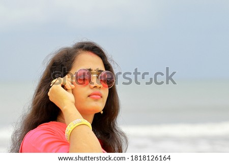 Indian beautiful woman wearing pink colored Traditional Rajasthani rajputi clothes and shiny glasses and out of focus beach background , A happy female modal looking at camera , closeup face beauty