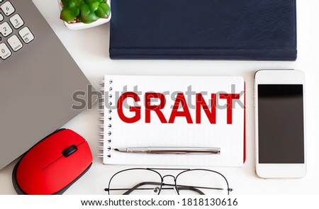 GRANT text with fountain pen, decorative plant, keyboard and notepad on wooden background. Business concept
