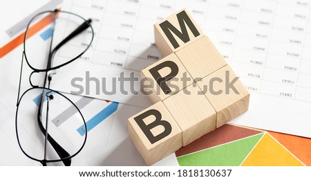 BPM words with wooden blocks on chart background. Business concept.