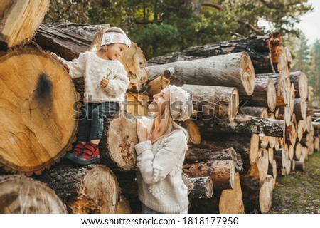 Little girl enjoying and hugging with young blonde mother. Toddler kid playing outdoors in autumn forest. Outdoor active fun for family vacation.