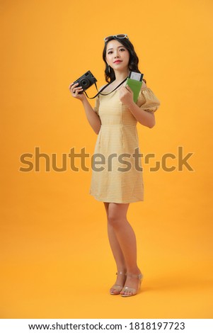 Excited girl holding passport tickets with photo camera isolated on gray wall background