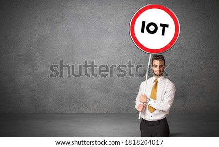 Young business person holdig traffic sign with IOT abbreviation, technology solution concept