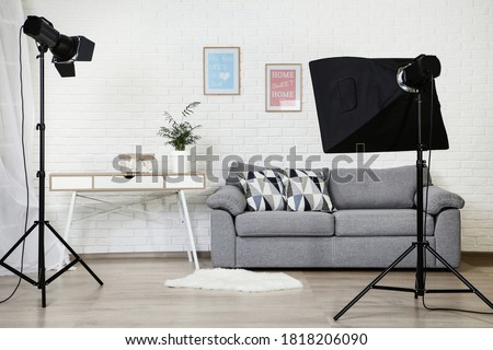 Photo studio with professional equipment and home interior on brick wall background Royalty-Free Stock Photo #1818206090