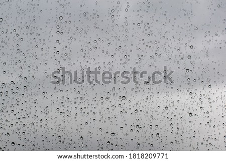 Rain drop texture on car glass overcast sky background