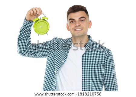 Young man with green alarm clock isolated on white background