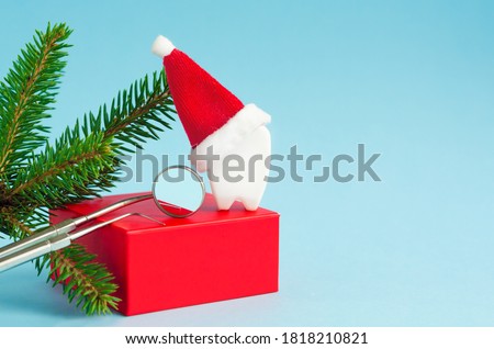 tools, mirror, probe, tooth in Santa hat on red podium for new year on blue background. creative medical stomatology christmas card. Health care, dental hygiene concept. free space Royalty-Free Stock Photo #1818210821