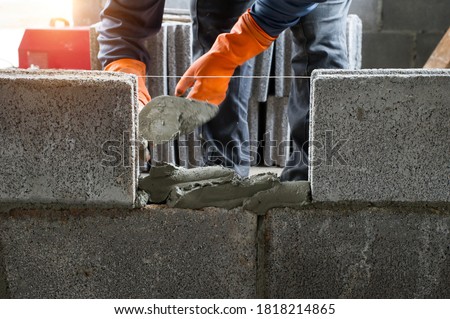 masonry worker make concrete wall by cement block and plaster at construction site Royalty-Free Stock Photo #1818214865