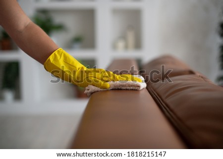 Professional cleaning service, housekeeping. Hygiene and cleanliness in the kitchen. ACleaning lady with gloves wipes dust from furniture with a cloth Royalty-Free Stock Photo #1818215147