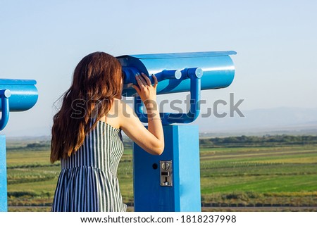 the young woman looking through binoculars